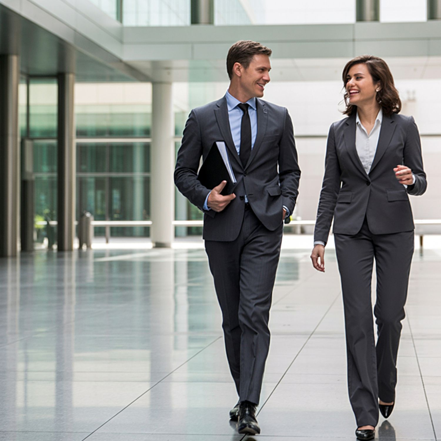 Dos profesionales caminando y conversando en un espacio corporativo